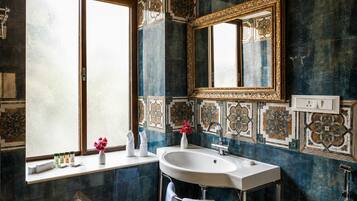 Un baño con un espejo grande, un lavamanos y azulejos decorativos.