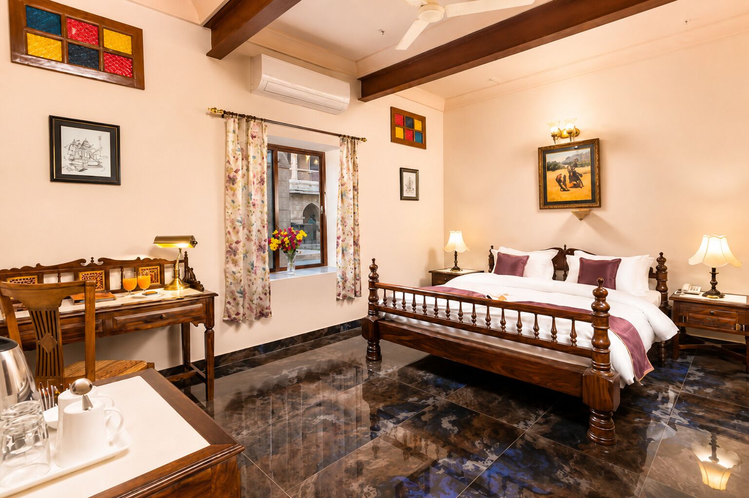Quarto de hotel com cama, mesas de cabeceira, escrivaninha, cadeira, janela com cortinas e um quadro na parede.