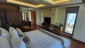 Une chambre d’hôtel avec un grand lit, un bureau avec une télévision, une armoire et une fenêtre donnant sur un beau paysage.
