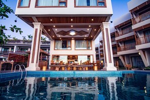 Un hotel moderno con piscina, que cuenta con un bar y zona de estar al aire libre.
