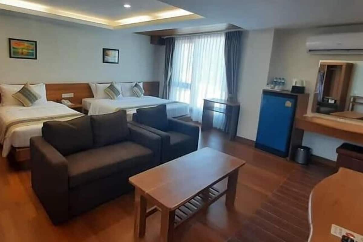 Una habitación de hotel con dos camas, un sofá, una mesita y un escritorio con espejo.