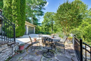 Eine Terrasse mit Steinboden, Metallstühlen und einem Tisch.