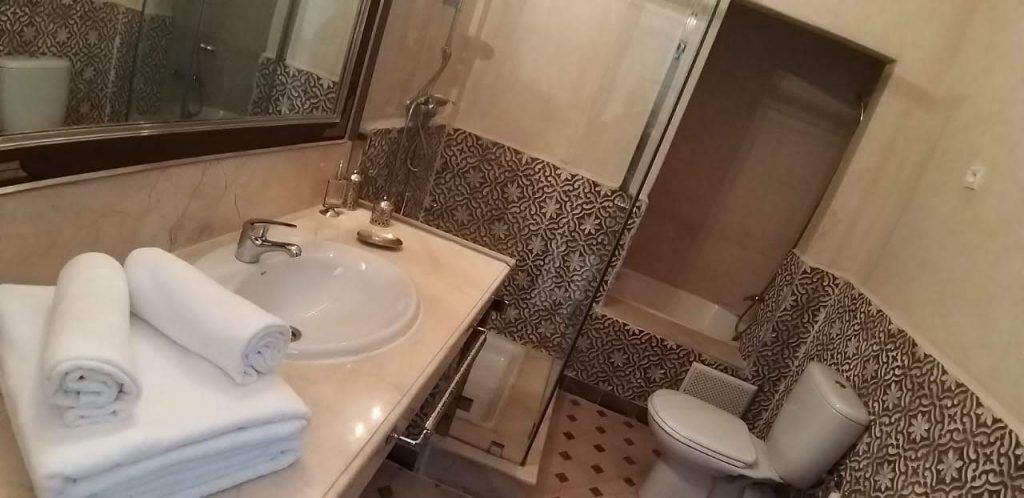 Un baño con lavamanos, espejo, inodoro y azulejos estampados.