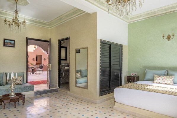 A bedroom with a bed, a nightstand, a mirror, and a chandelier.