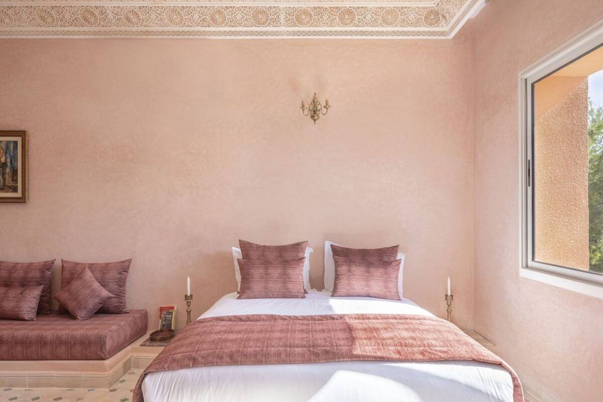 A bedroom with a bed, a sofa, and a window.