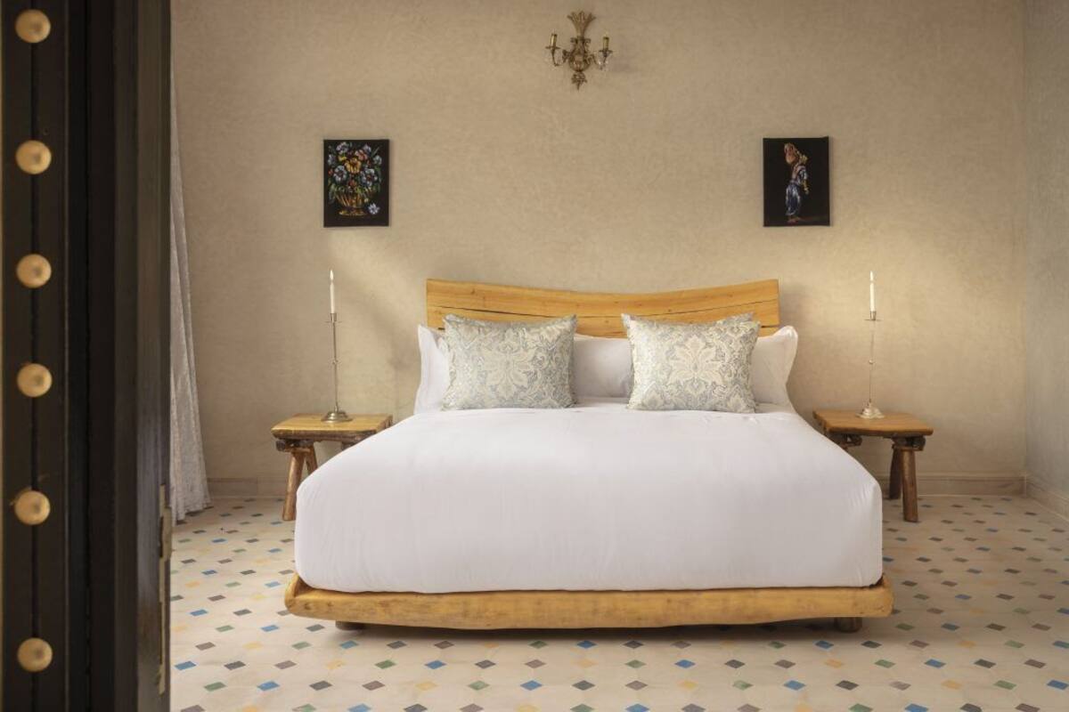 A neatly made bed with a wooden headboard, two bedside tables with lamps, and a patterned floor.