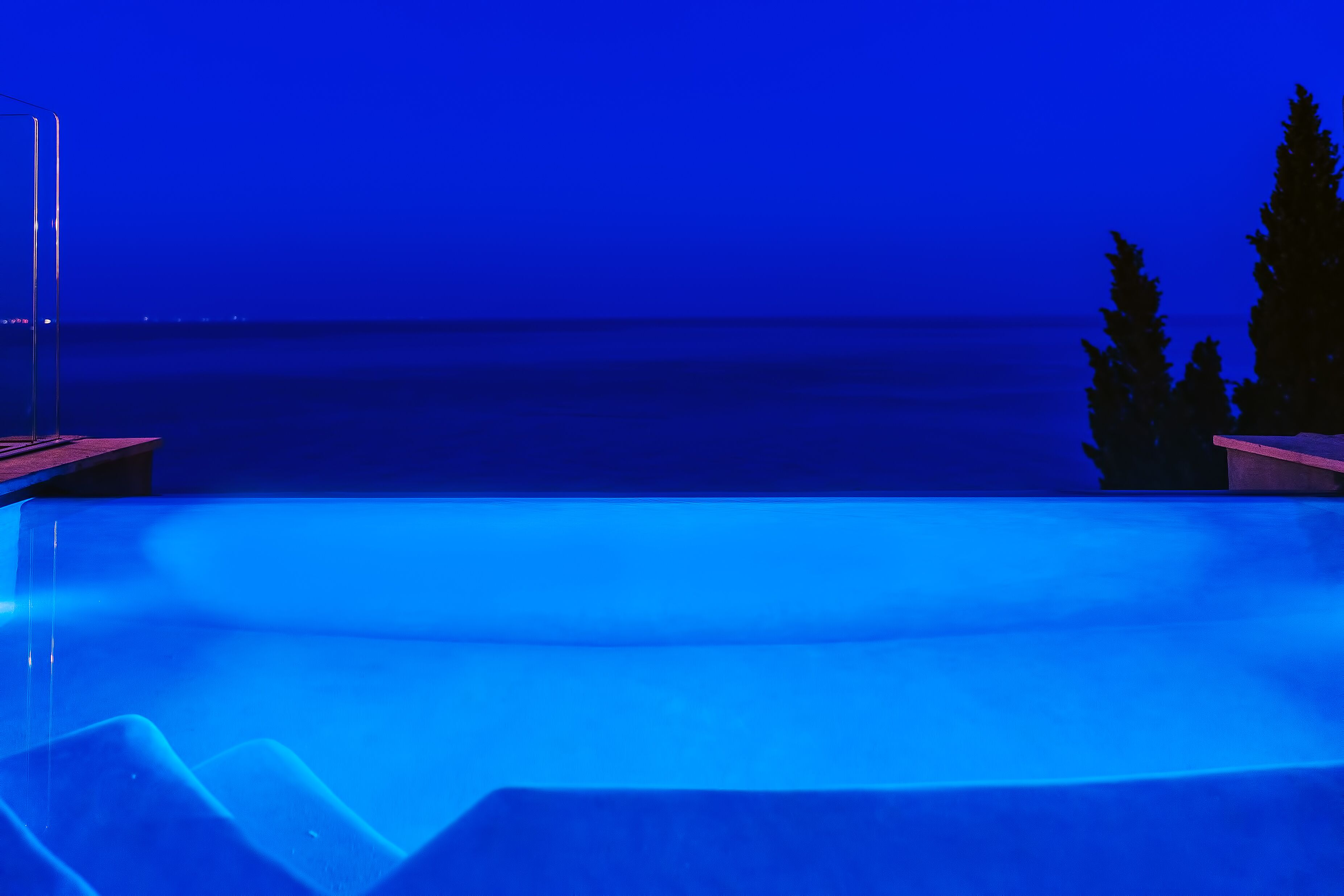 An infinity pool with a view of the ocean at night.