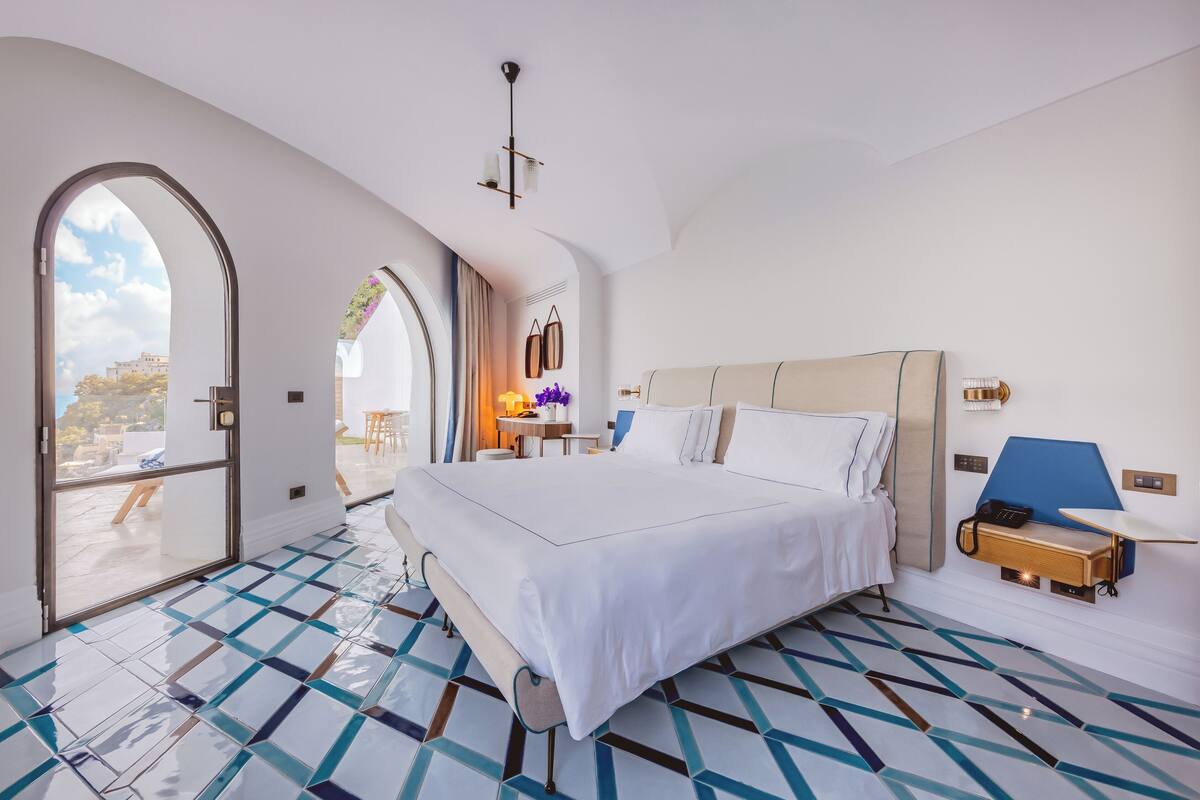 Een moderne hotelkamer met een groot bed, een bureau en een uitzicht door een gewelfde deuropening.