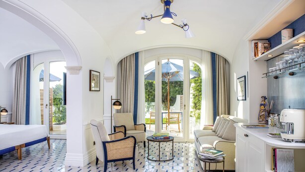 Habitación de hotel con un ventanal grande, una cama, un área de descanso con una mesita de café y una estantería.
