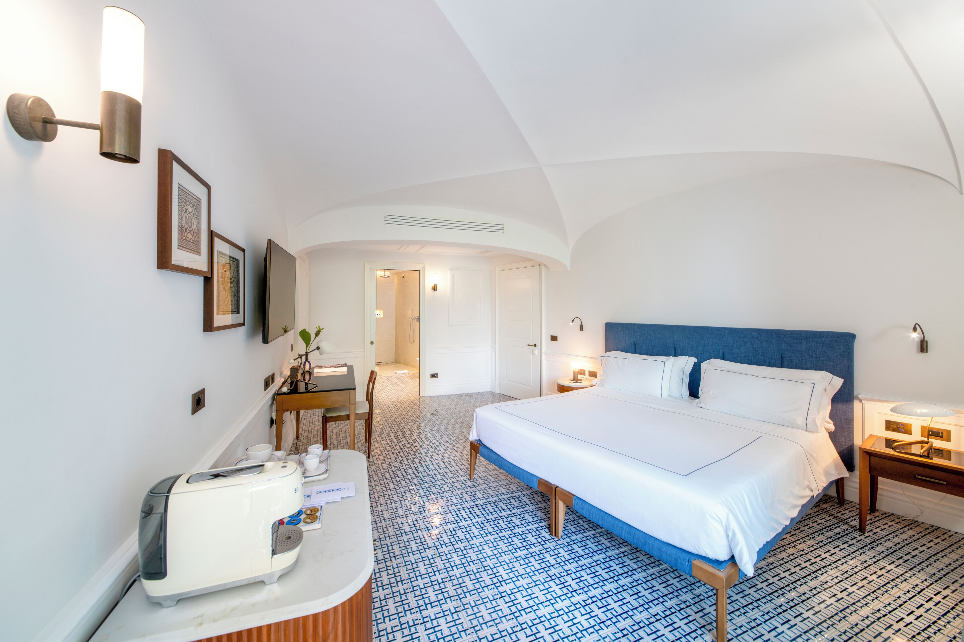 Une chambre d’hôtel avec un grand lit, un bureau avec une chaise, un grille-pain et une petite table avec une plante.