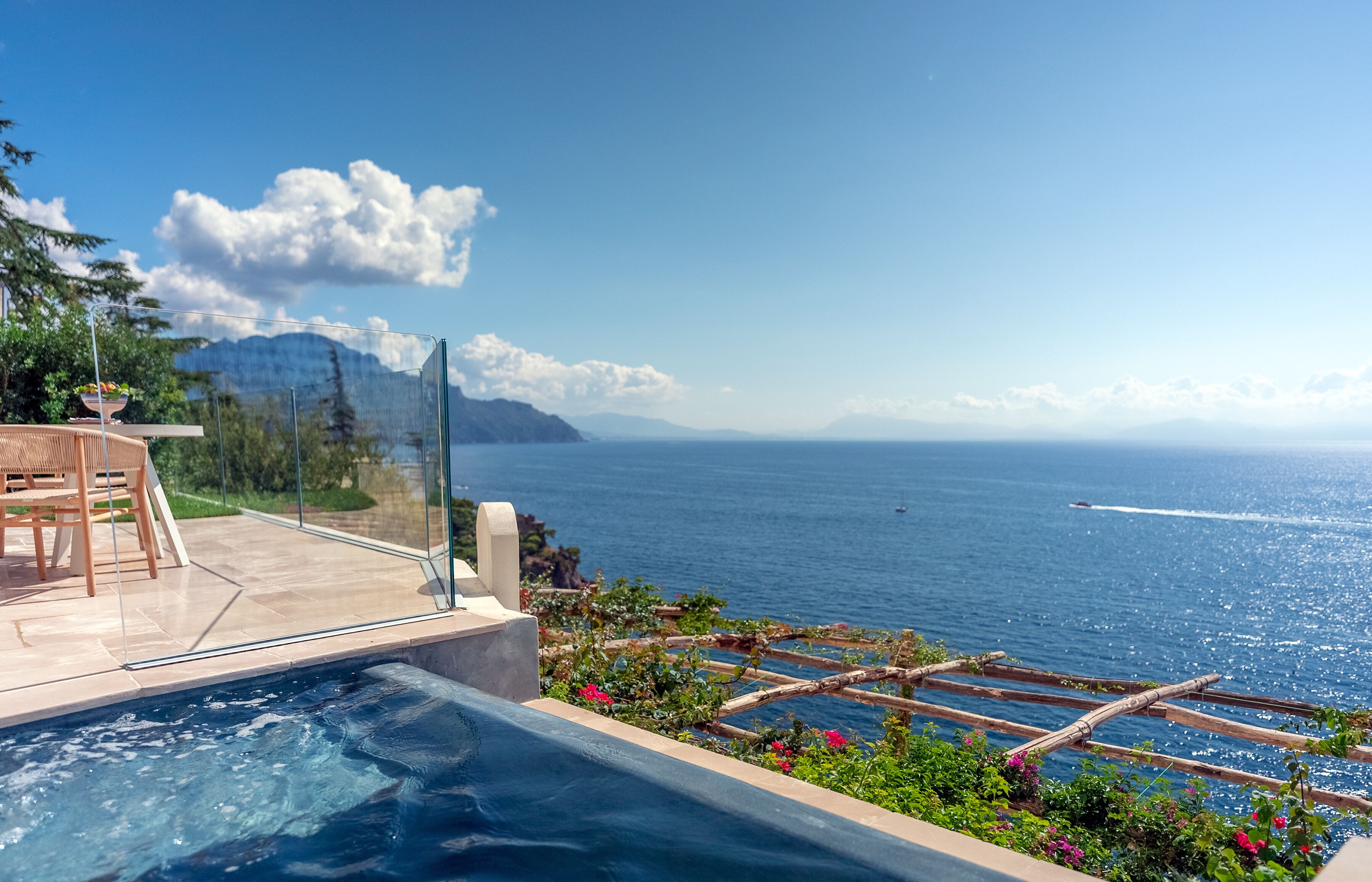Ein Pool mit freiem Blick auf das Meer und die dahinter liegenden Berge.
