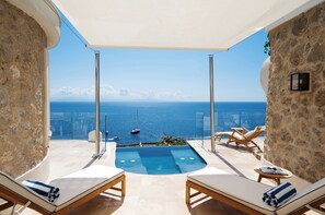 Terraza en la azotea con piscina, sillones de descanso y vistas al mar.