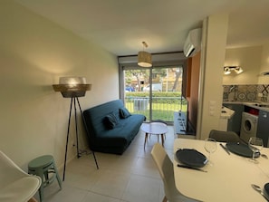Un espacio habitable compacto con sofá, mesa de comedor y zona de cocina.