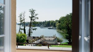 A view of a lake with boats, surrounded by trees and a building with a balcony. - Gästehaus am Lehnitzsee (Potsdam)