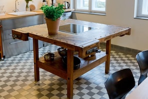 Une cuisine avec une table en bois, une plante en pot et divers ustensiles de cuisine.
