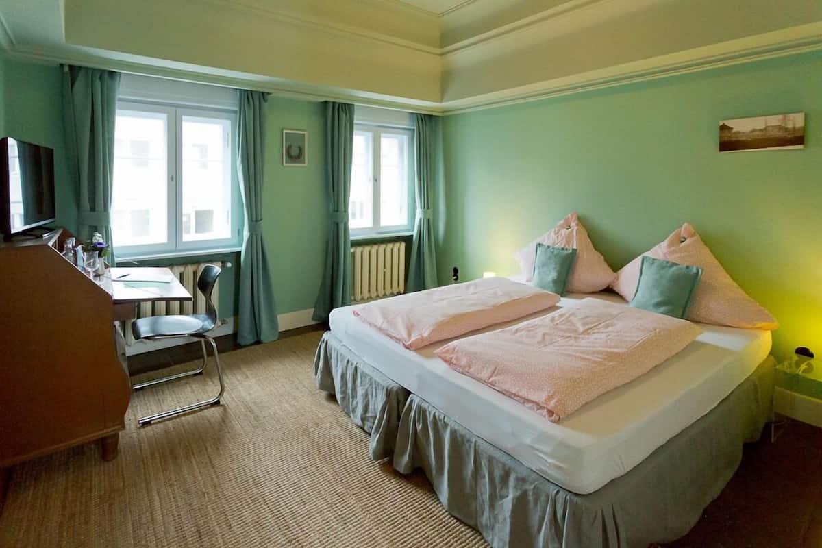 Ein Hotelzimmer mit Bett, Schreibtisch, Stuhl und Fernseher.