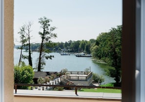 Une vue d’un lac avec des bateaux, entouré d’arbres et d’un bâtiment doté d’un balcon.