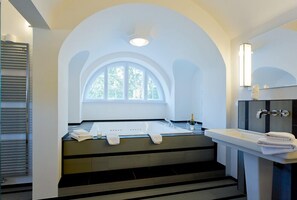 A modern bathroom with a bathtub, a sink, and a window. - Gästehaus am Lehnitzsee (Potsdam)