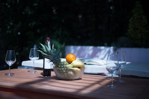 A wooden table with a fruit bowl containing pineapple, banana, and orange, and two empty wine glasses. - Aparthouse - Villa Napoleon (Jelsa)