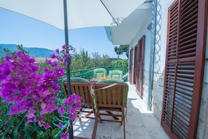 A balcony with two wooden chairs, a table, and purple flowers. - Aparthouse - Villa Napoleon (Jelsa)