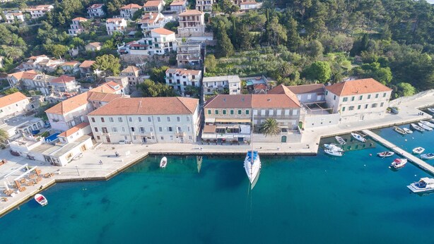 An aerial view of a coastal town with a marina, buildings with red-tiled roofs, and a clear blue waterfront. - Aparthouse - Villa Napoleon (Jelsa)