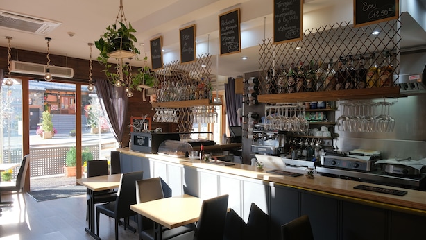 Ein Restaurantinneres mit Bar, Sitzgelegenheiten und Blick nach außen.