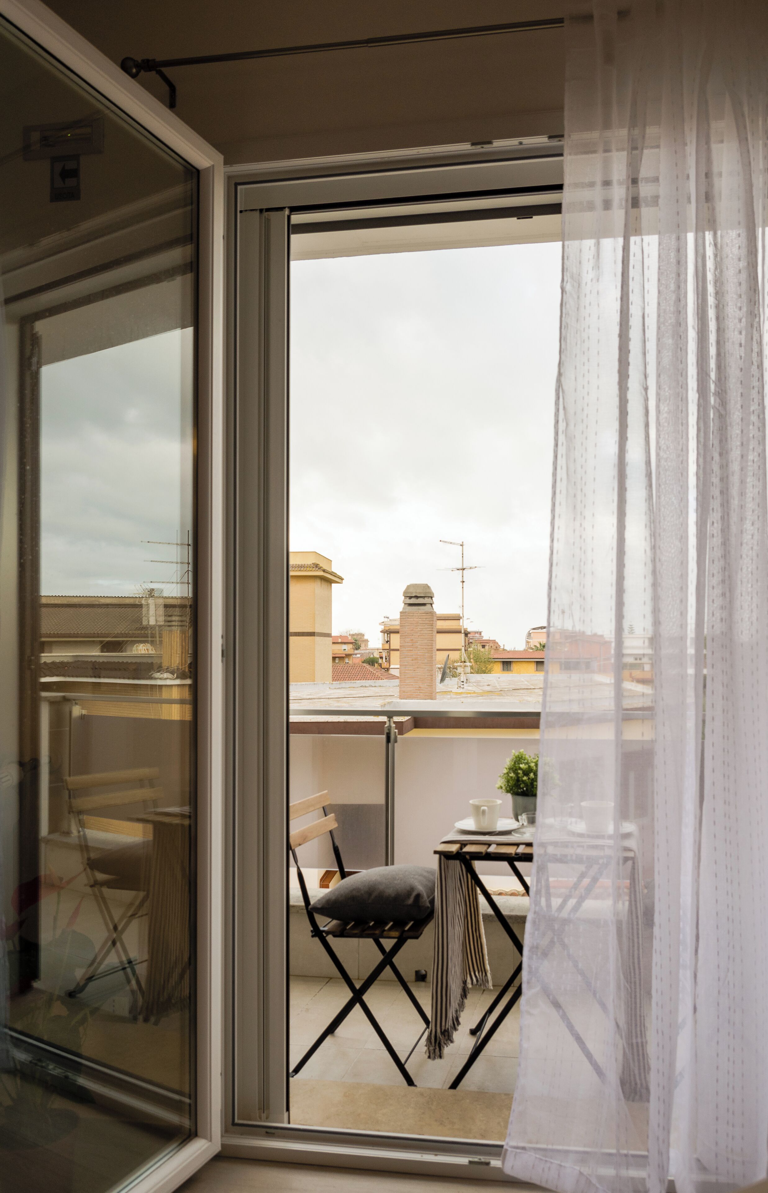 A balcony with a table, chairs, and a view of buildings in the background.