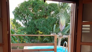 A wooden deck with a pool, surrounded by lush greenery and trees. - VillaRosa Guadeloupe (Sainte-Rose)