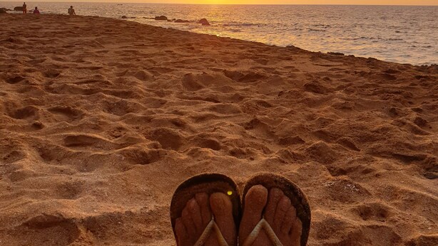 A beach scene with a sunset, featuring a pair of flip-flops on the sand. - VillaRosa Guadeloupe (Sainte-Rose)