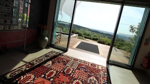 A room with a large sliding glass door leading to an outdoor deck with a view of the countryside. - Hotel La Montagne de Brancion (Martailly-Les-Brancion)
