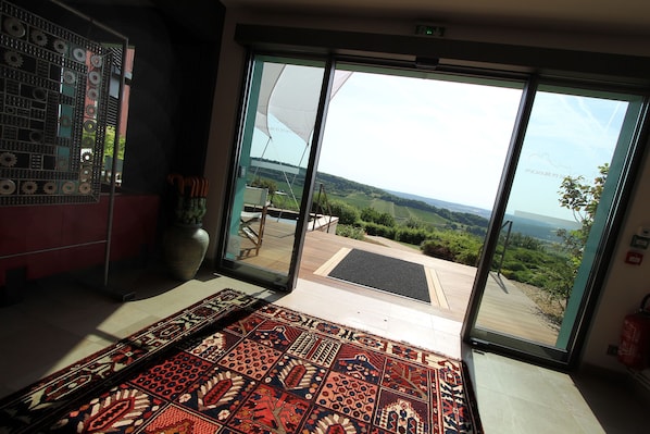 A room with a large sliding glass door leading to an outdoor deck with a view of the countryside.