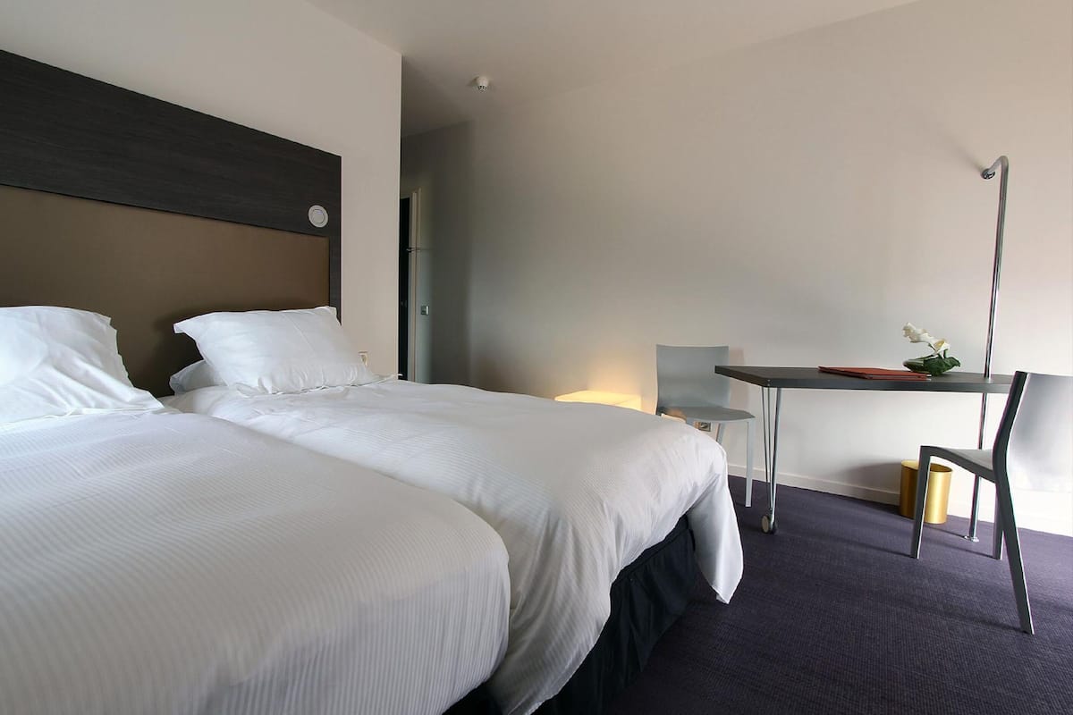 Une chambre d’hôtel avec deux lits, un bureau et une chaise.