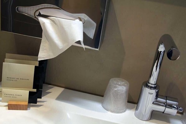 A bathroom with a modern sink, a towel hanging on a towel rack, and a glass container.