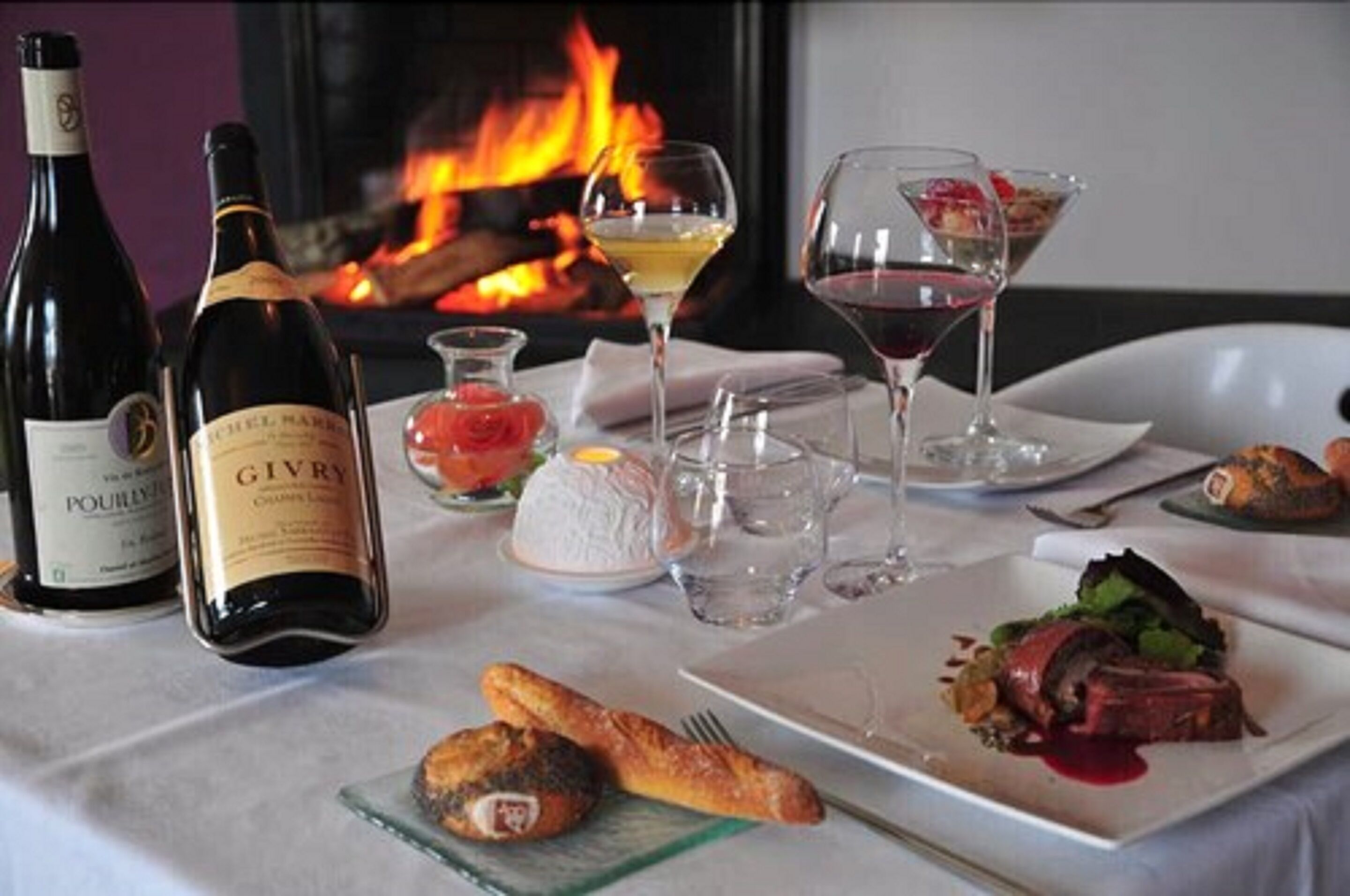 Une table à manger avec des bouteilles de vin, des verres et des assiettes remplies de nourriture.