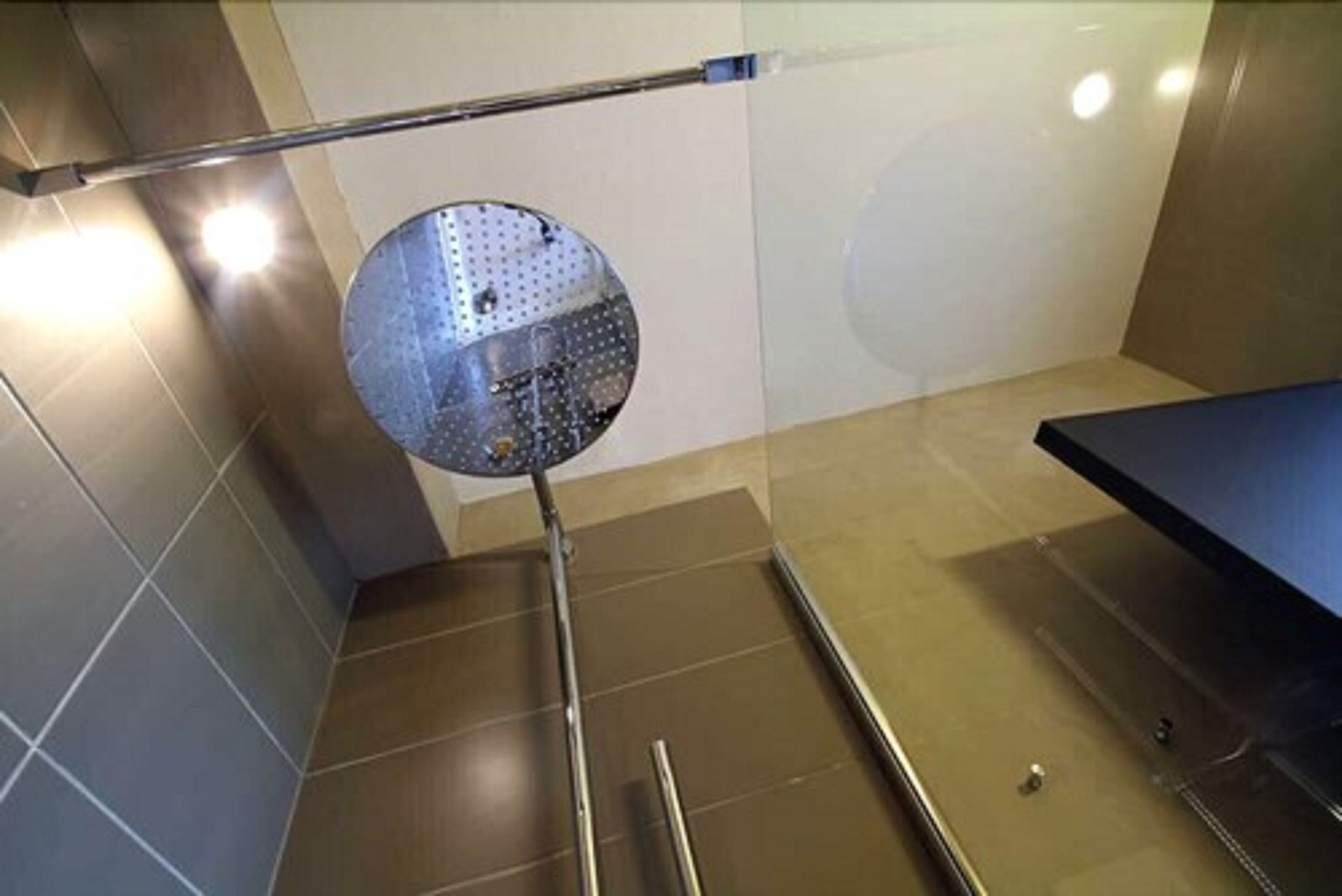 Una habitación con un espejo grande, un poste de metal y un banco azul.