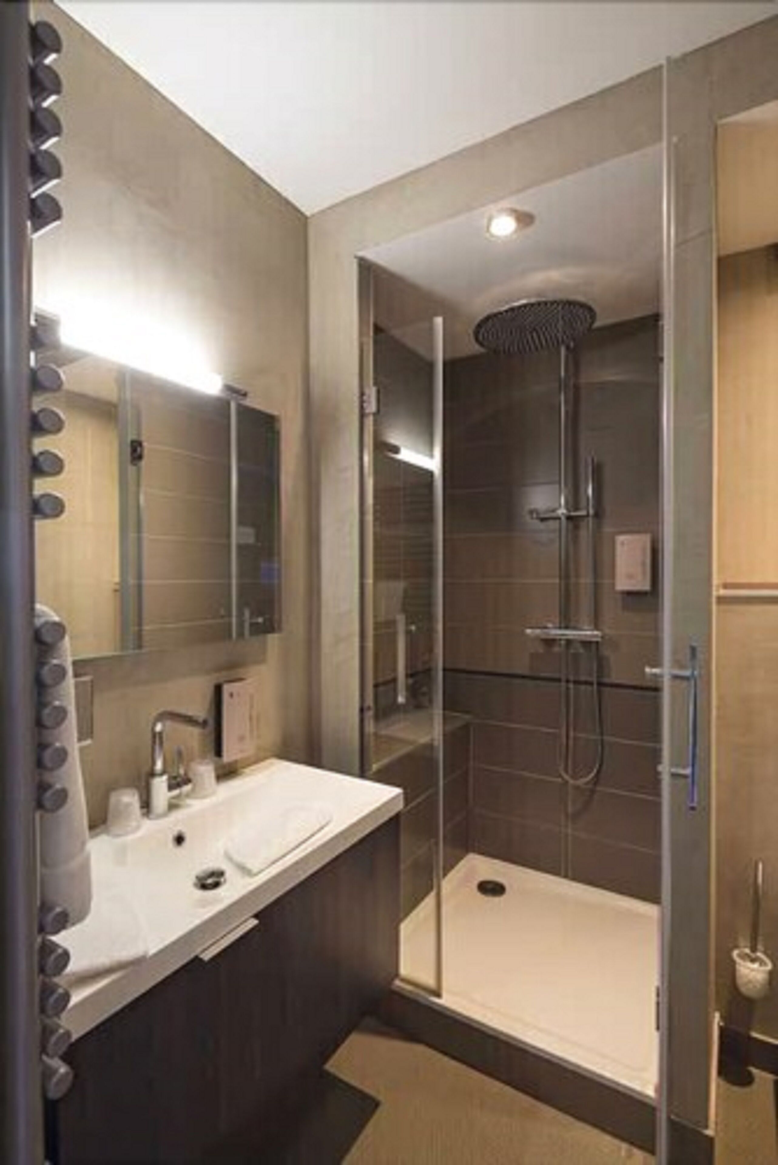 Un bagno moderno con doccia vetrata, un lavabo con specchio e un lavandino.