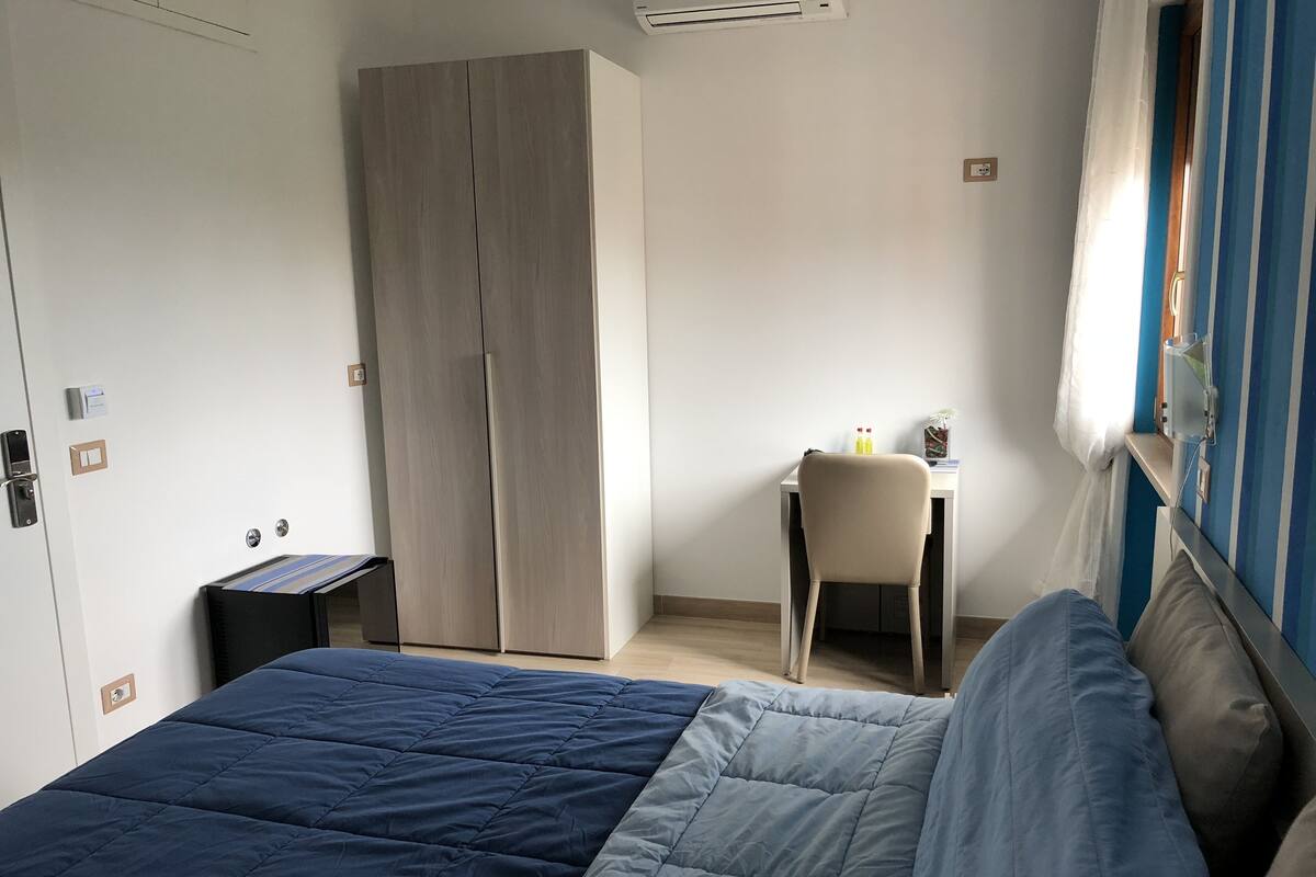 A bedroom with a bed, a desk, and a wardrobe.