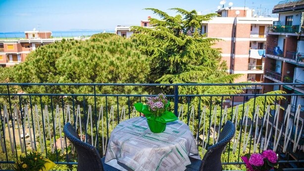 A balcony with a table and chairs, a potted plant, and a view of buildings and trees. - English Inn rooms (Sorrento)