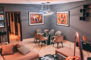 A modern living room with a glass dining table, comfortable seating, and artwork on the walls. - Appart F3 Deluxe Carré Eden (Marrakech)