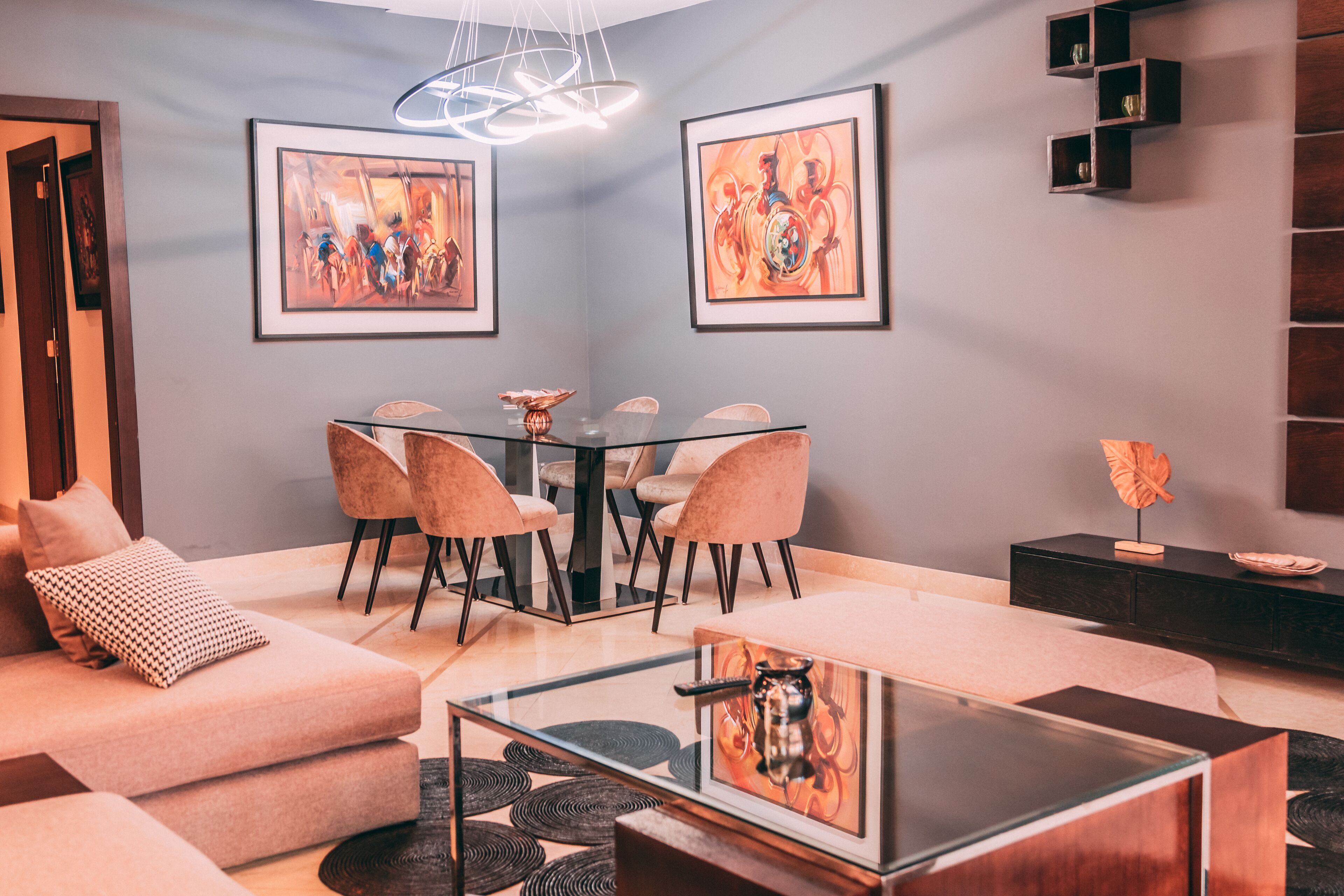 A modern living room with a glass dining table, cushioned chairs, a sofa, and a coffee table.