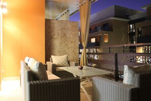 A balcony with wicker furniture, a glass table, and a view of the building's interior. - Appart F3 Deluxe Carré Eden (Marrakech)