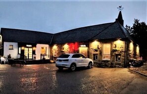 A building with a stone facade, a sloped roof, and a car parked in front. - The 1645 Inn (Nairn)