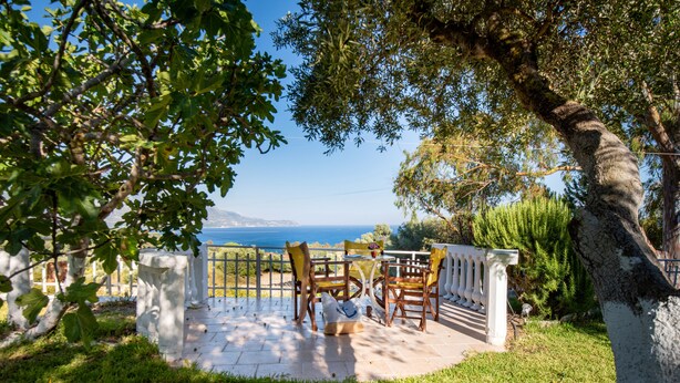 Un patio con mobiliario exterior, una cerca blanca y vista al mar.
