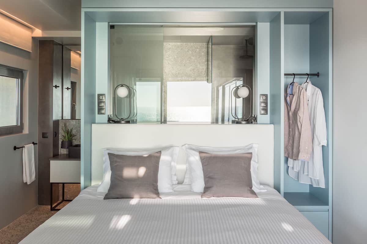A modern bedroom with a large bed, a vanity with a mirror, and a hanging robe rack.