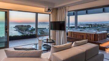 Una sala de estar moderna con un sofá grande, una mesa de centro y vistas a una masa de agua y un horizonte urbano distante.
