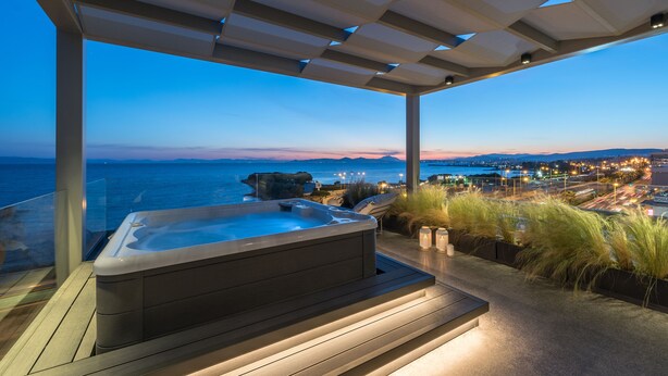 A hot tub under a pergola with a view of the ocean and city lights. - Urban Suites (Alimos)