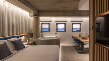 Un dormitorio moderno con una cama grande, un escritorio integrado y vistas al mar a través de ventanas.