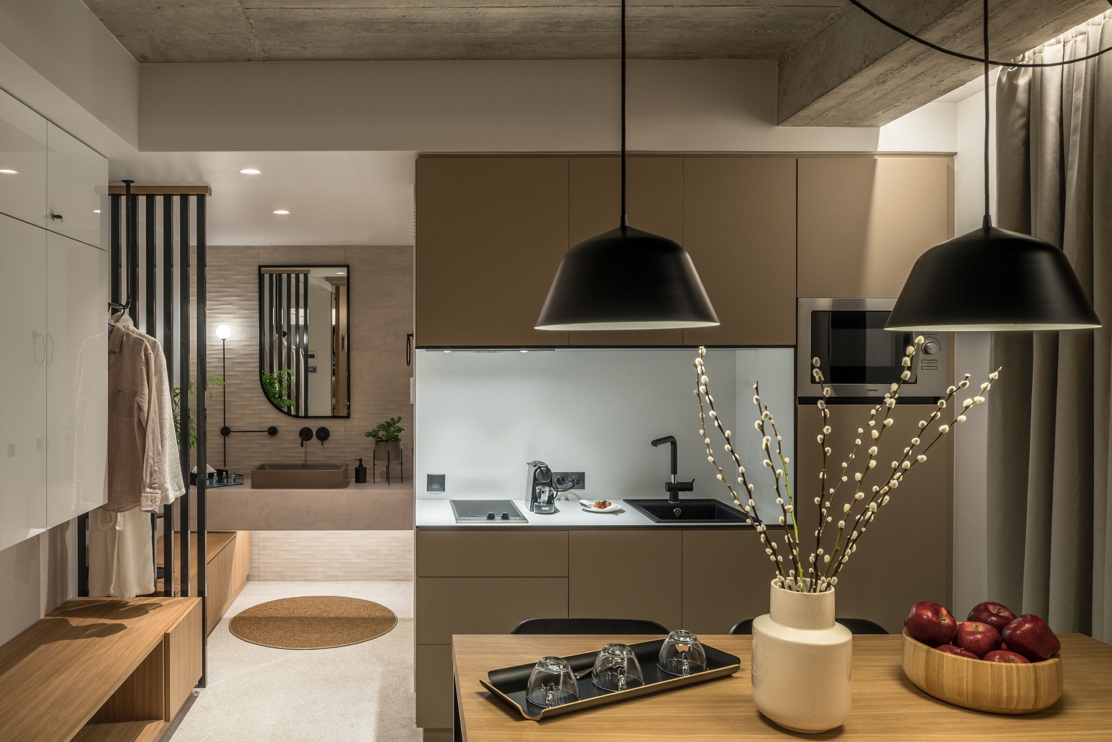 A modern kitchen with a central island, a dining area with a wooden table, and a large mirror.