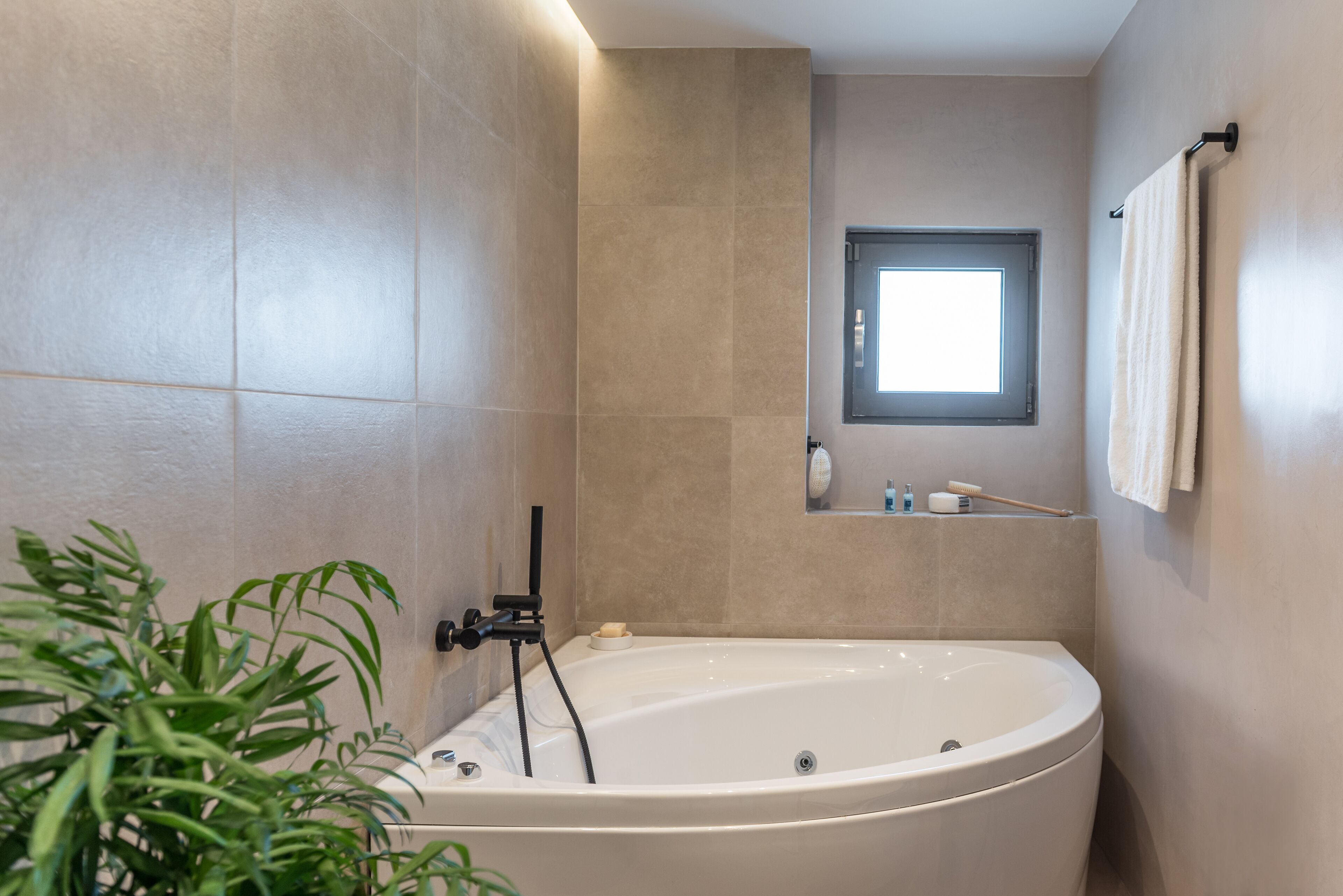 A modern bathroom with a freestanding bathtub, a small window, and a towel rack.
