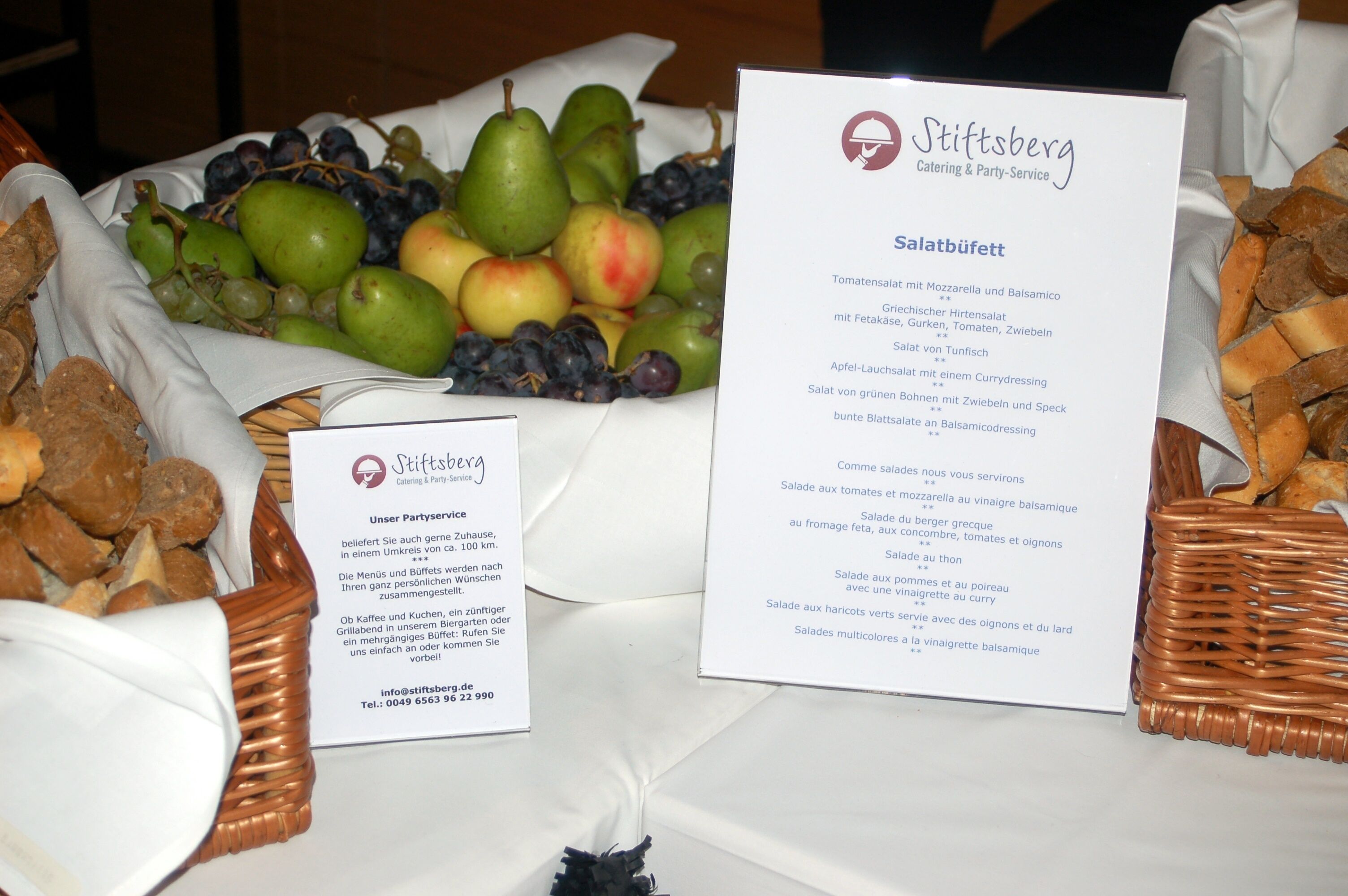 Een tafel met een menukaart voor 'Salatbüffel' en een bordje voor 'Stiftsberg Catering & Party-Service'.